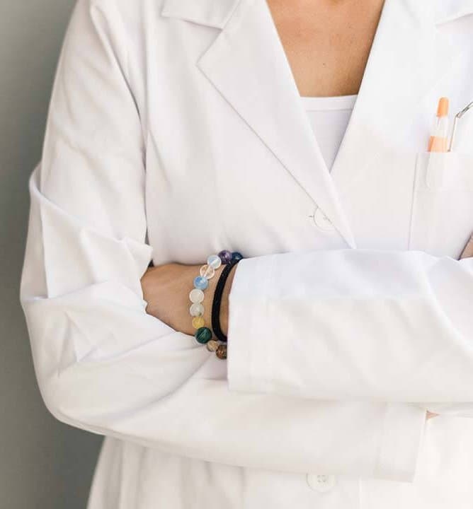 A dentist in a white coat with arms folded